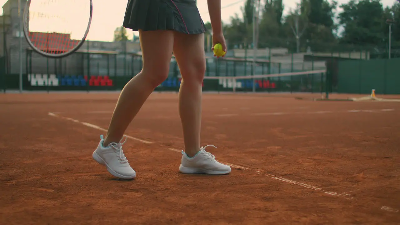 For tennis training a girl stands on the central service line Bangs the ball on the court Serve the camera moves from the ground to medium close-up