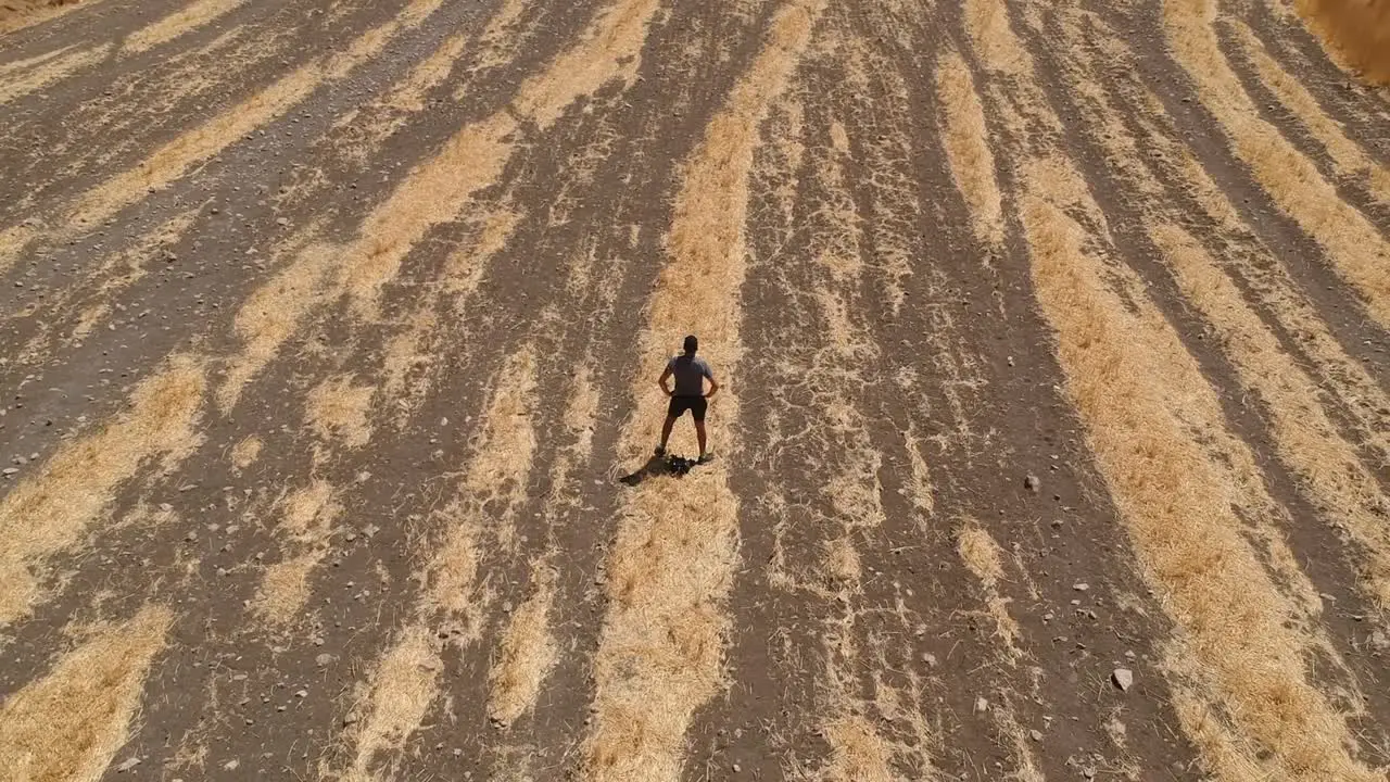 Person running through arid brown field from aerial view with drone