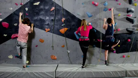 Teenage boys and girl climbing indoors