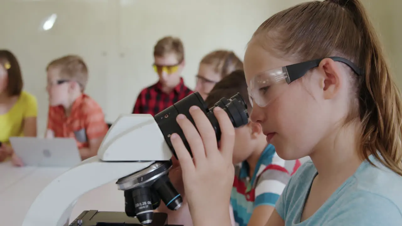 Girl wearing glasses using microscope 