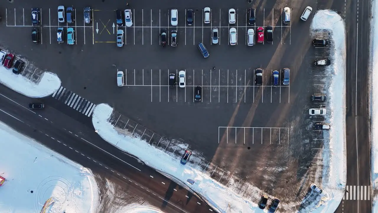 City parking vehicles leaving the parking lot seen from above on a winter day