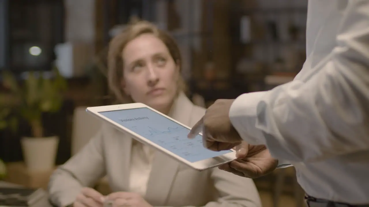 Close Up View Of Unrecognizable American Man Employee Holding A Tablet And Explaining Graphics To Female Coworkers Who Are Sitting At Desk In The Office