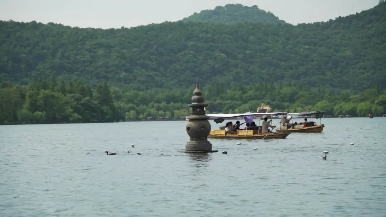 Tourist boats on the West Lake and one of the Three Stone Pagodas from the Three Pools Mirroring the Moon Hangzhou China