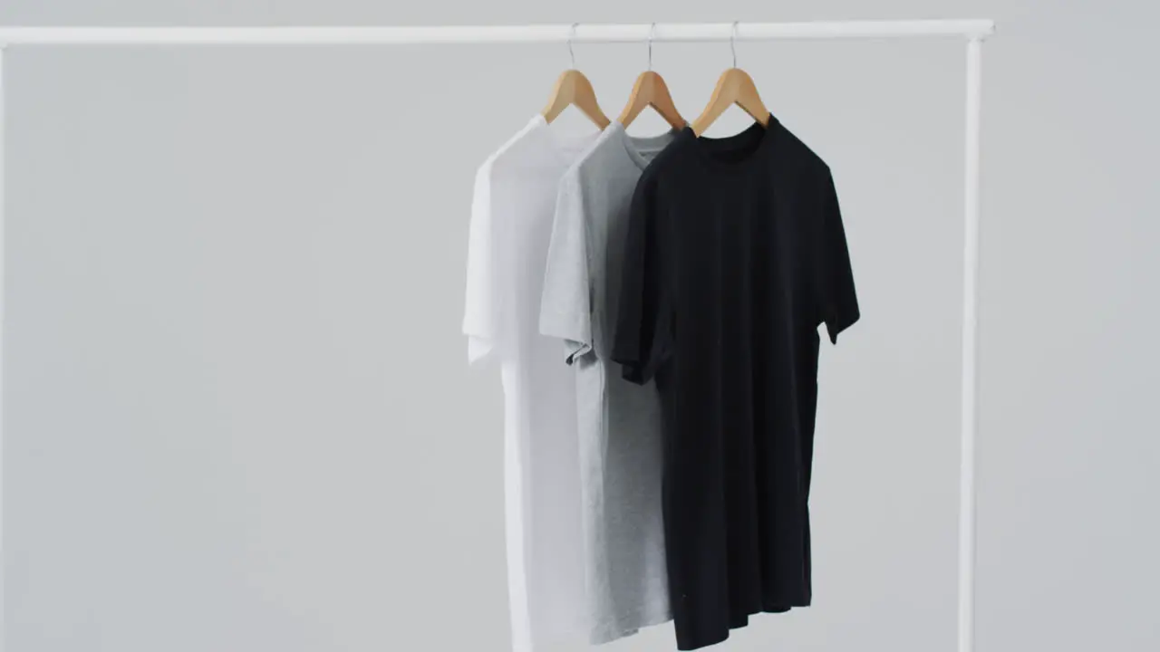 Video of white grey black t shirts on hangers and copy space on white background