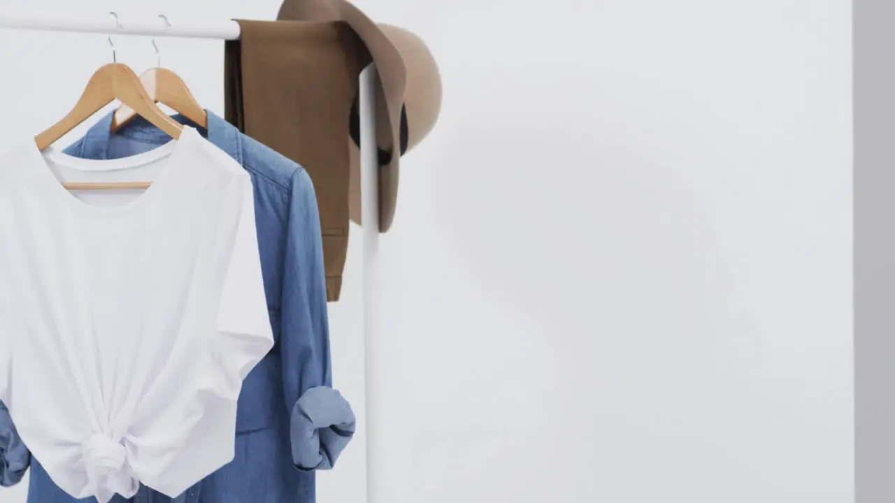 Video of white and denim t shirt on hangers hat and copy space on white background