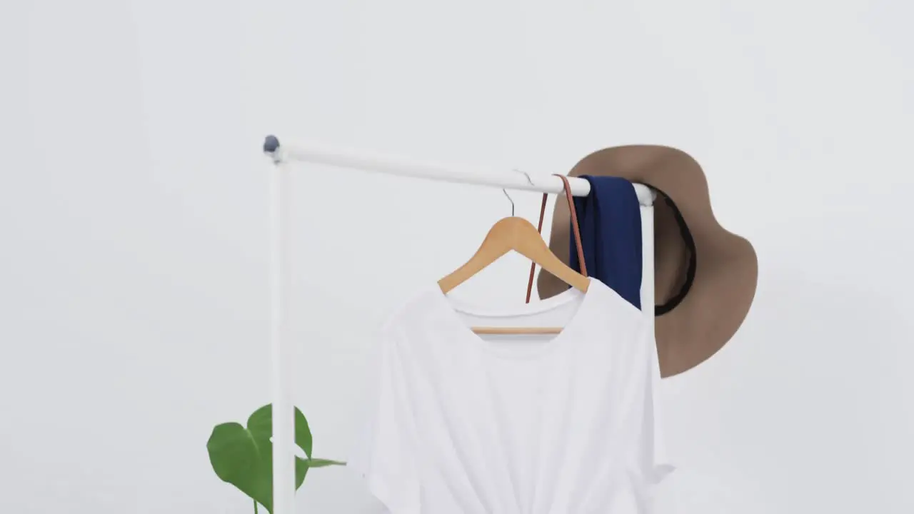 Video of white t shirt on hanger with hat and copy space on white background