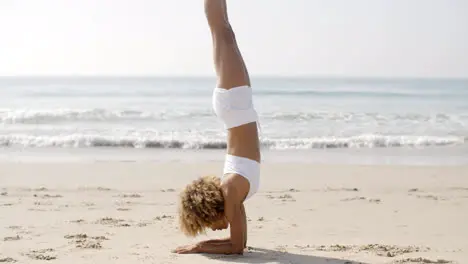 Woman Practicing Yoga On The Beach