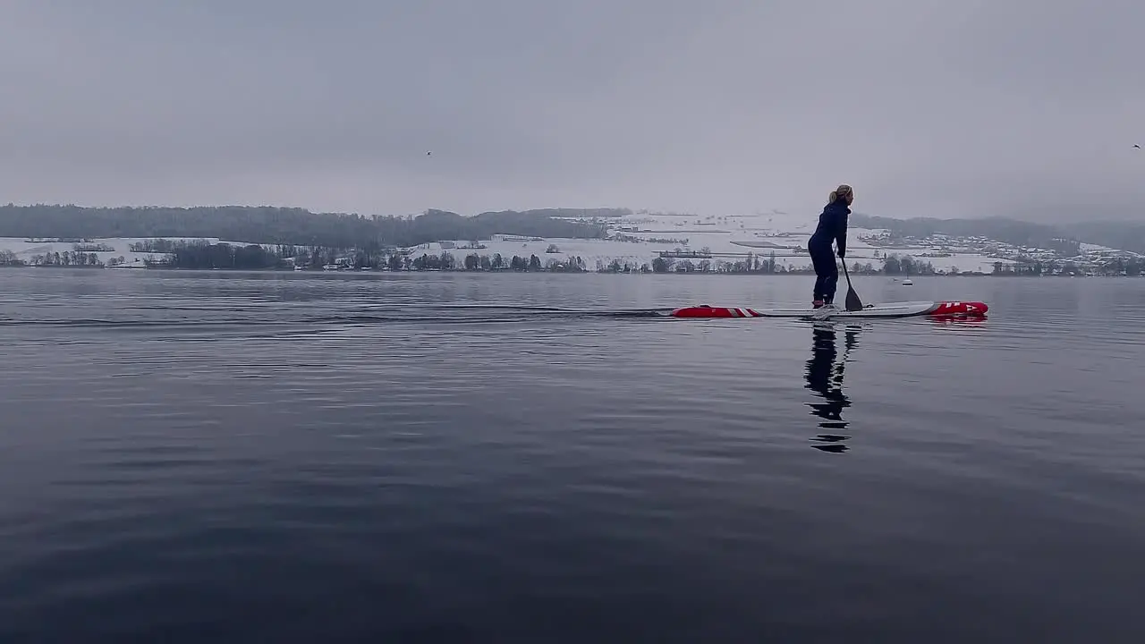 Slow motion footage of a woman on a stand-up-paddleboard SUP on a lake in Switzerland in winter