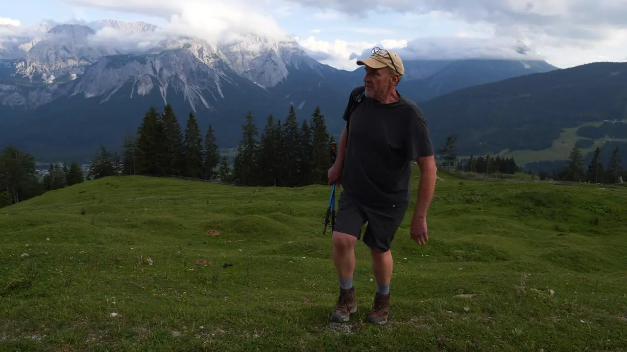 Man walking up grass hill mountain in the Austrian Alps peak