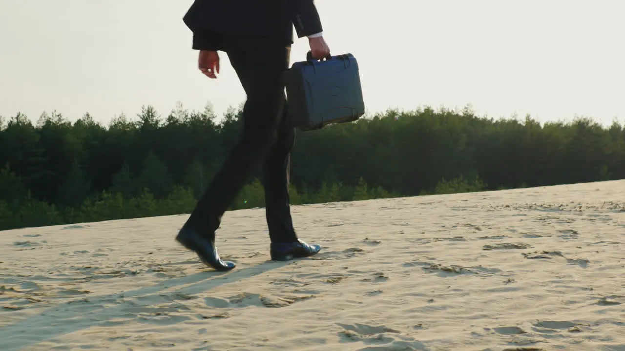 A businessman with a case in his hand walks along a sandy beach 1