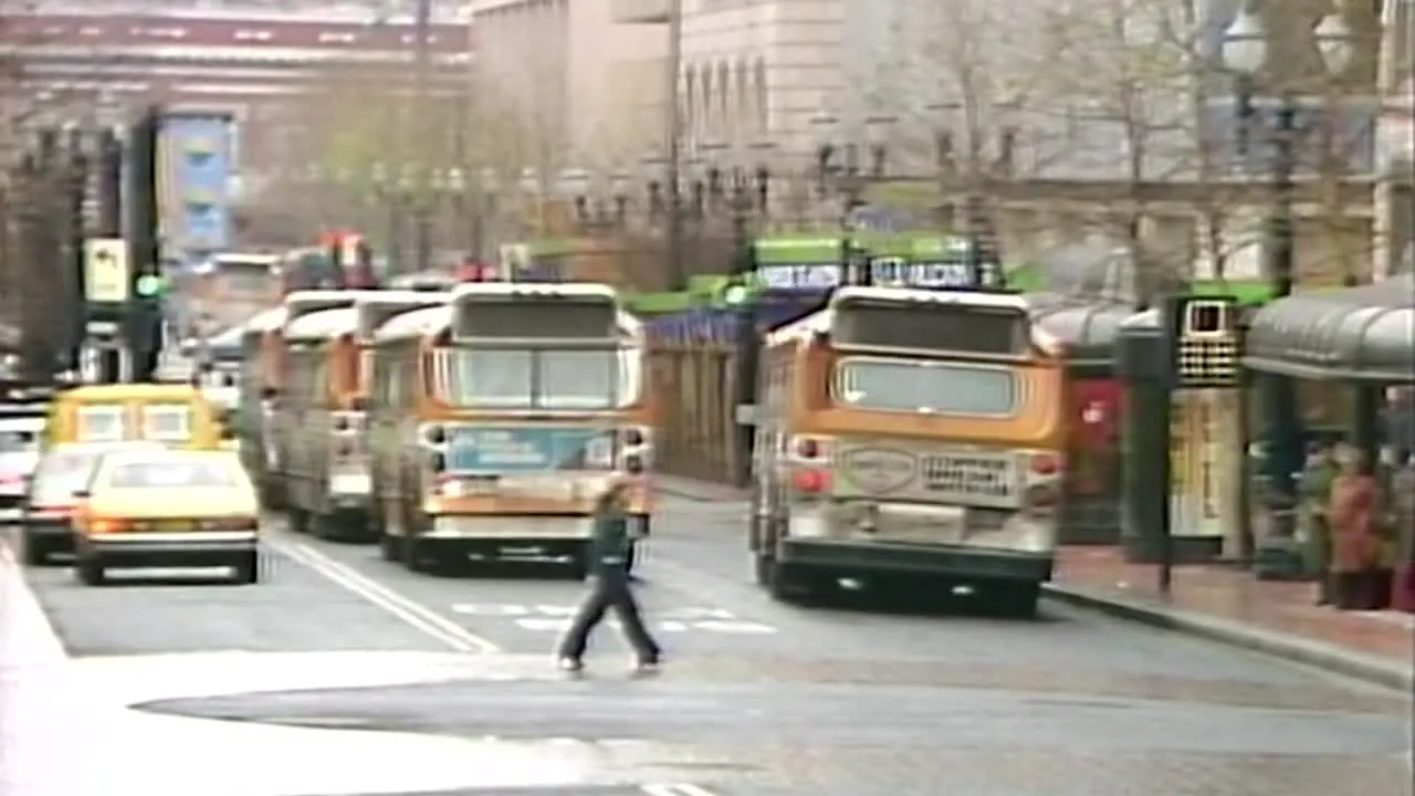 1980S DOWNTOWN PORTLAND CITY BUSES DRIVING AWAY DOWN STREET