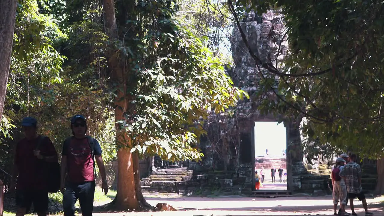 Tourists Walking Along a Tree Lined Path Through the Temples of Angkor Wat