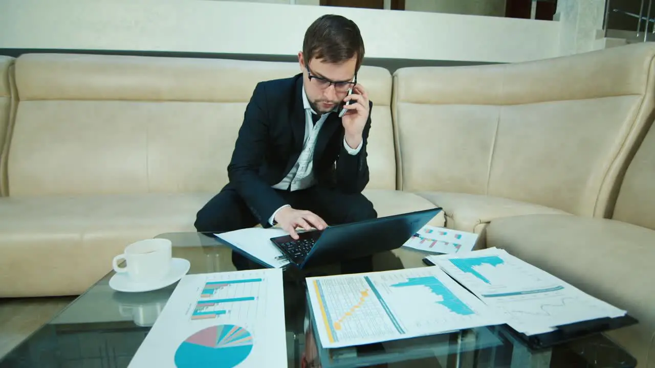 Young businessman working with documents and laptop in hotel lobby 1