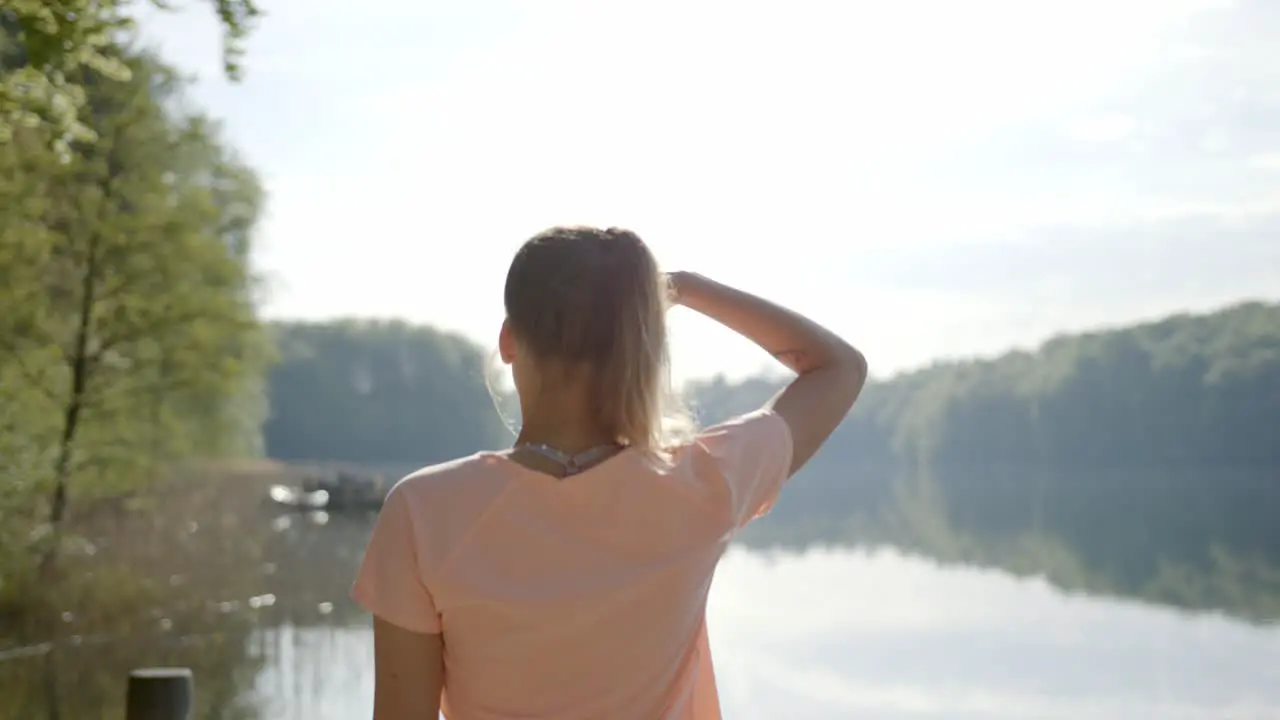 Woman walking to lakeside and viewing water on sunny day