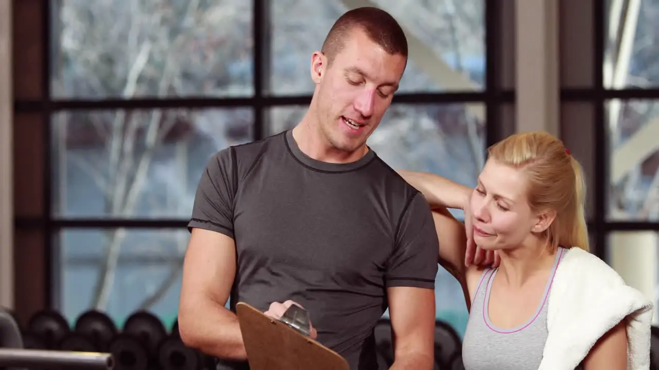 Trainer talking to his client in gym