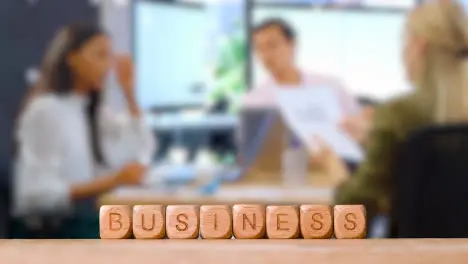 Business Concept Wooden Letter Cubes Or Dice Spelling Business With Office Meeting In Background