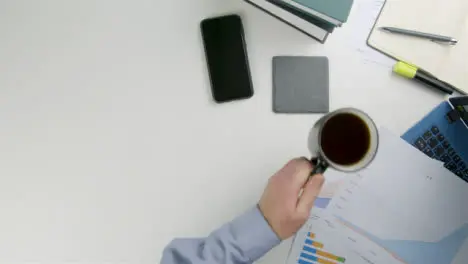 Businessman Taking a Drink of Coffee Before Placing It Back Down