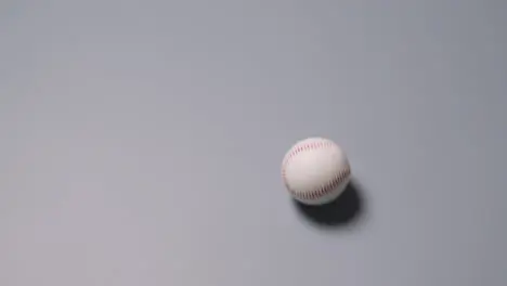 Overhead Shot Of Baseball Ball Rolling Across Frame Against Grey Background 1