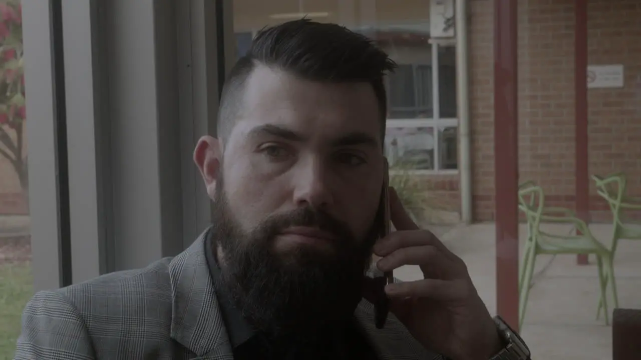 Man wearing a suit facing front on talking on a mobile phone