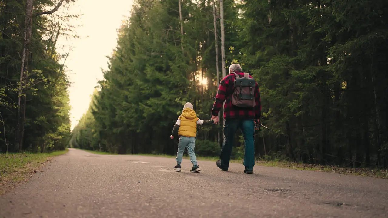 happy little boy and his granddad are walking to fishing in spring or autumn morning spending weekend together