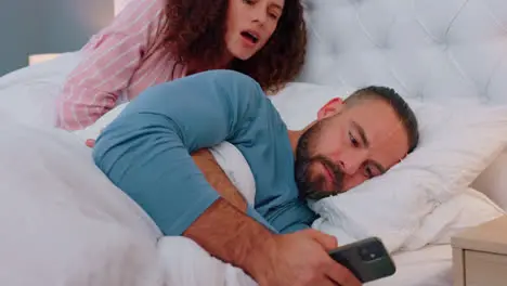 Jealous bed and woman reading phone communication