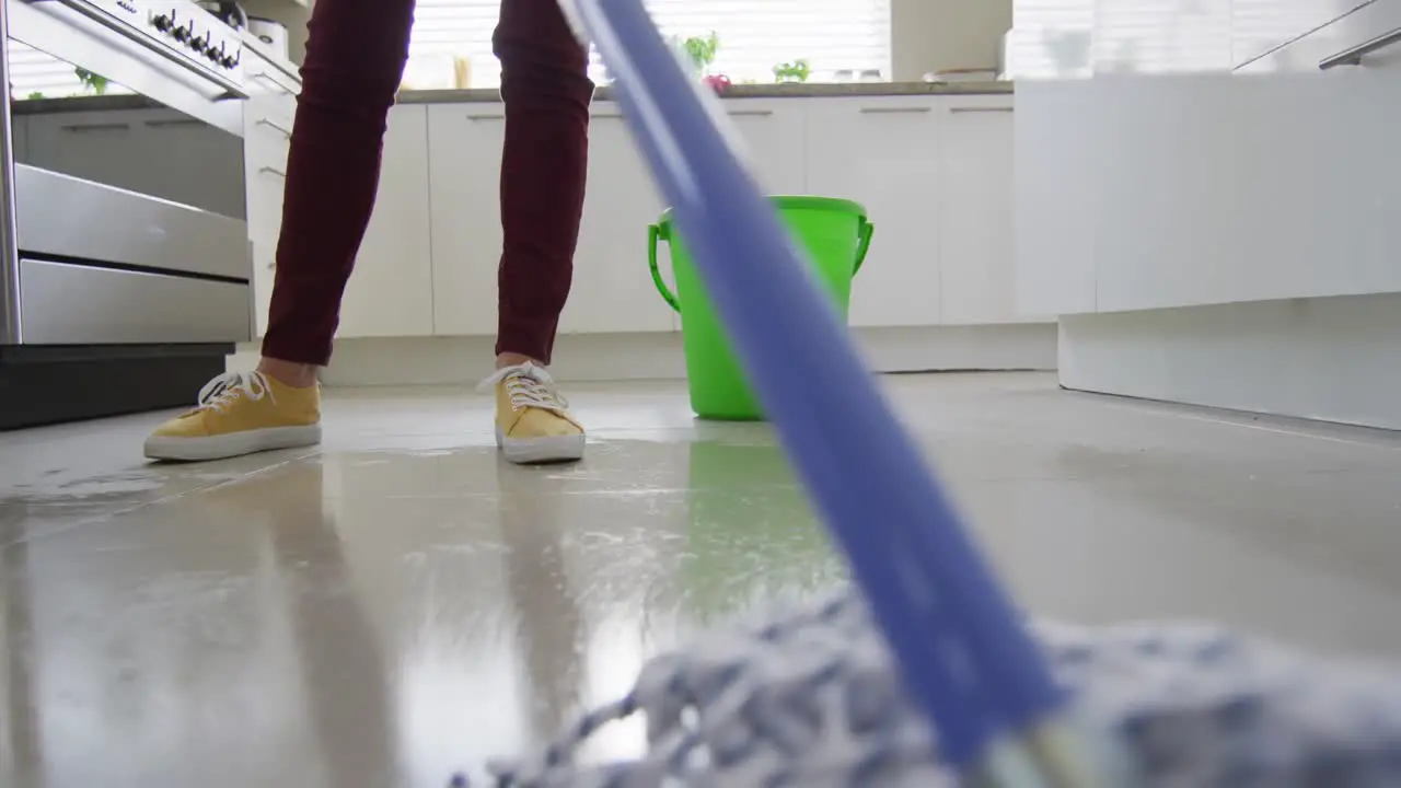 Caucasian woman cleaning floor with mop and bucket of water at home