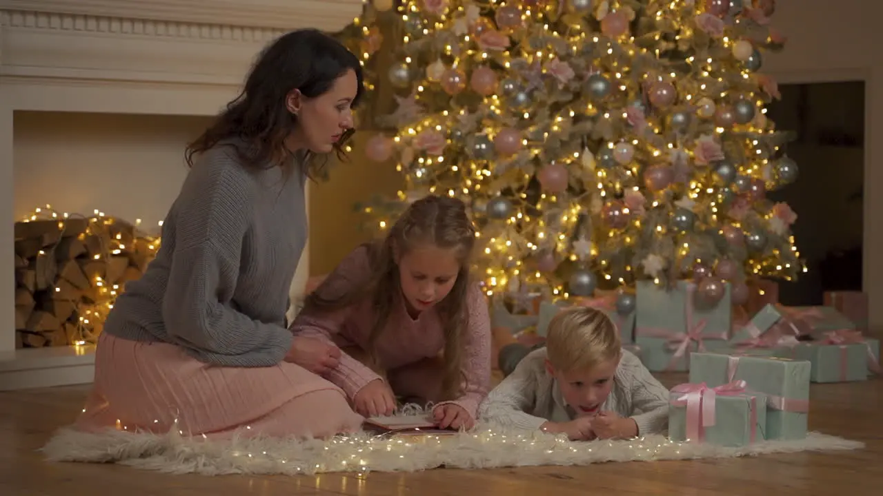 Kleine Jungen Und Mädchen Schreiben Einen Brief Mit Ihrer Mutter Auf Dem Boden Neben Den Geschenken Und Dem Weihnachtsbaum