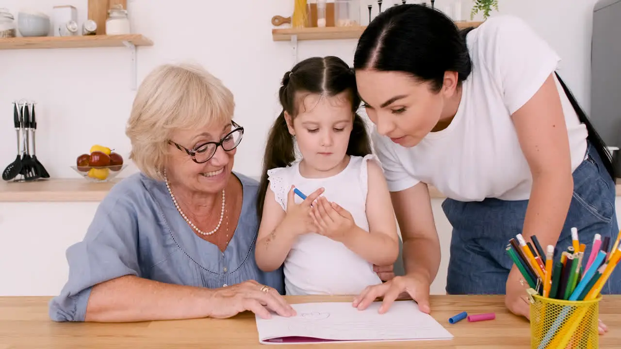 Großmutter Mutter Und Kleines Mädchen Schauen Während Eines Videoanrufs In Die Kamera Während Sie Sich Am Tisch In Der Küche Zusammenziehen