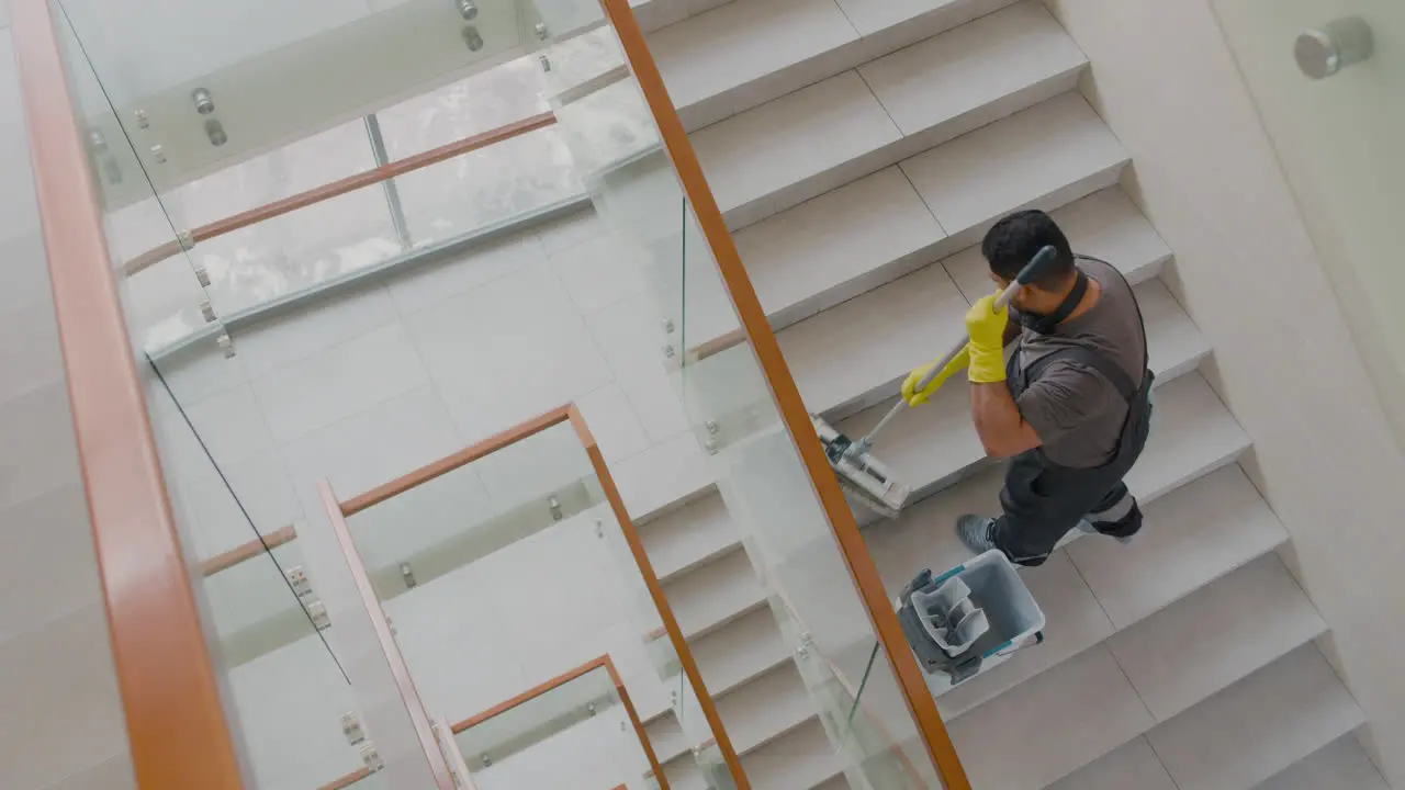 Blick Von Oben Auf Einen Arabischen Putzmann Mit Handschuhen Der Treppen Mit Mopp In Einem Bürogebäude Reinigt