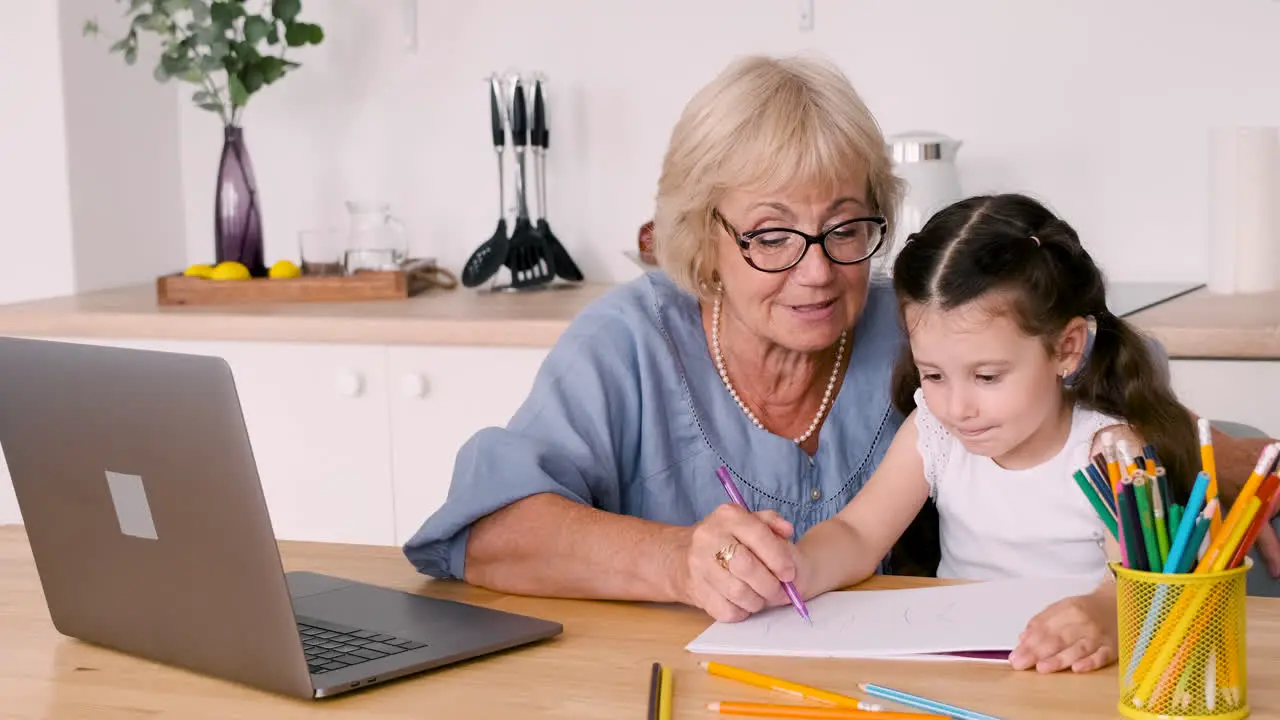 Großmutter Und Enkelin Zeichnen Am Tisch In Der Küche Sitzend Während Sie Einen Videoanruf Auf Einem Modernen Laptop Führen