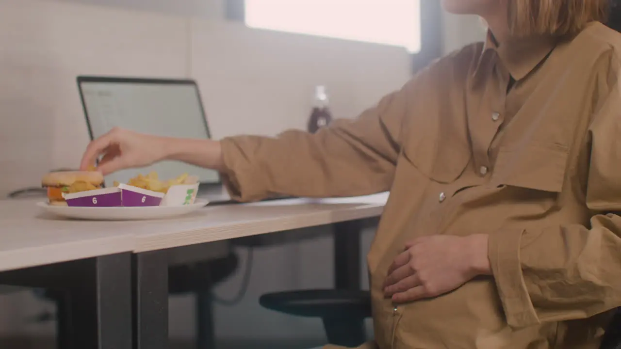 Cerca De Una Mujer Embarazada Que Trabaja Comiendo Pepitas Durante El Almuerzo De La Oficina