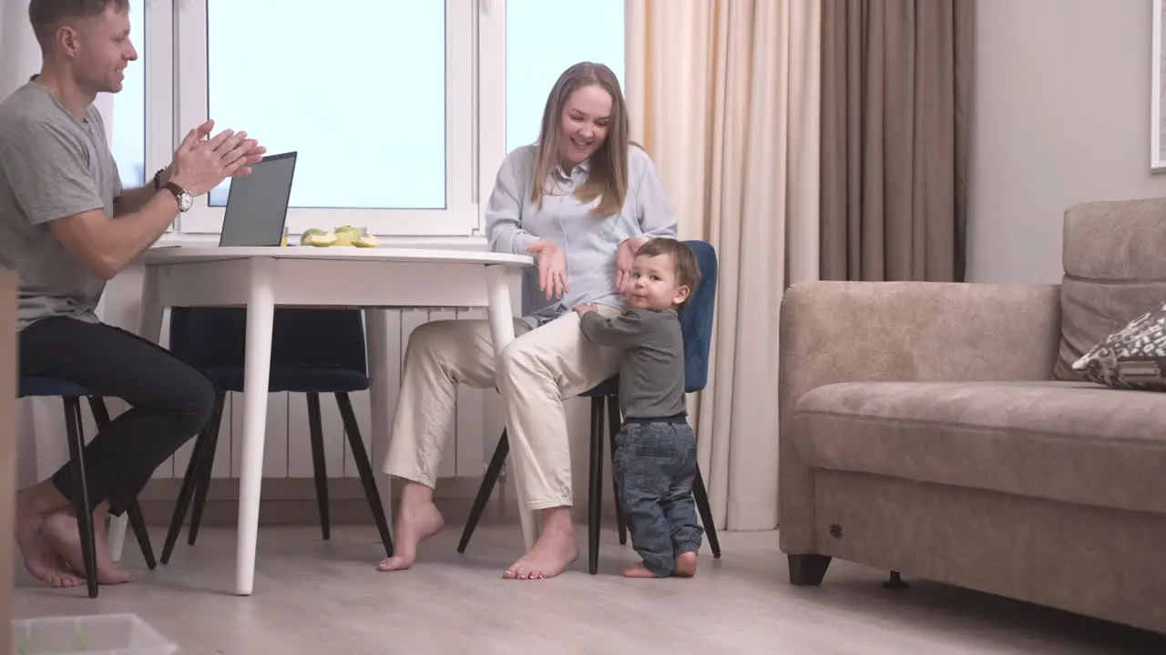 Vista Trasera De Un Bebé Dando Sus Primeros Pasos Hacia La Mesa Donde Están Sentados Sus Padres