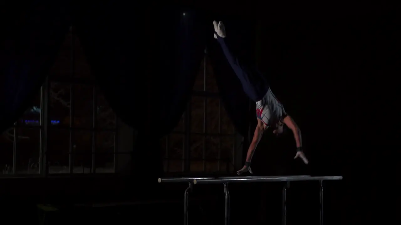 Un Gimnasta Acróbata Realiza Una Parada De Manos En Barras Paralelas En Una Habitación Oscura En Cámara Lenta Compartiendo Volteretas Y Aterrizando En El Suelo