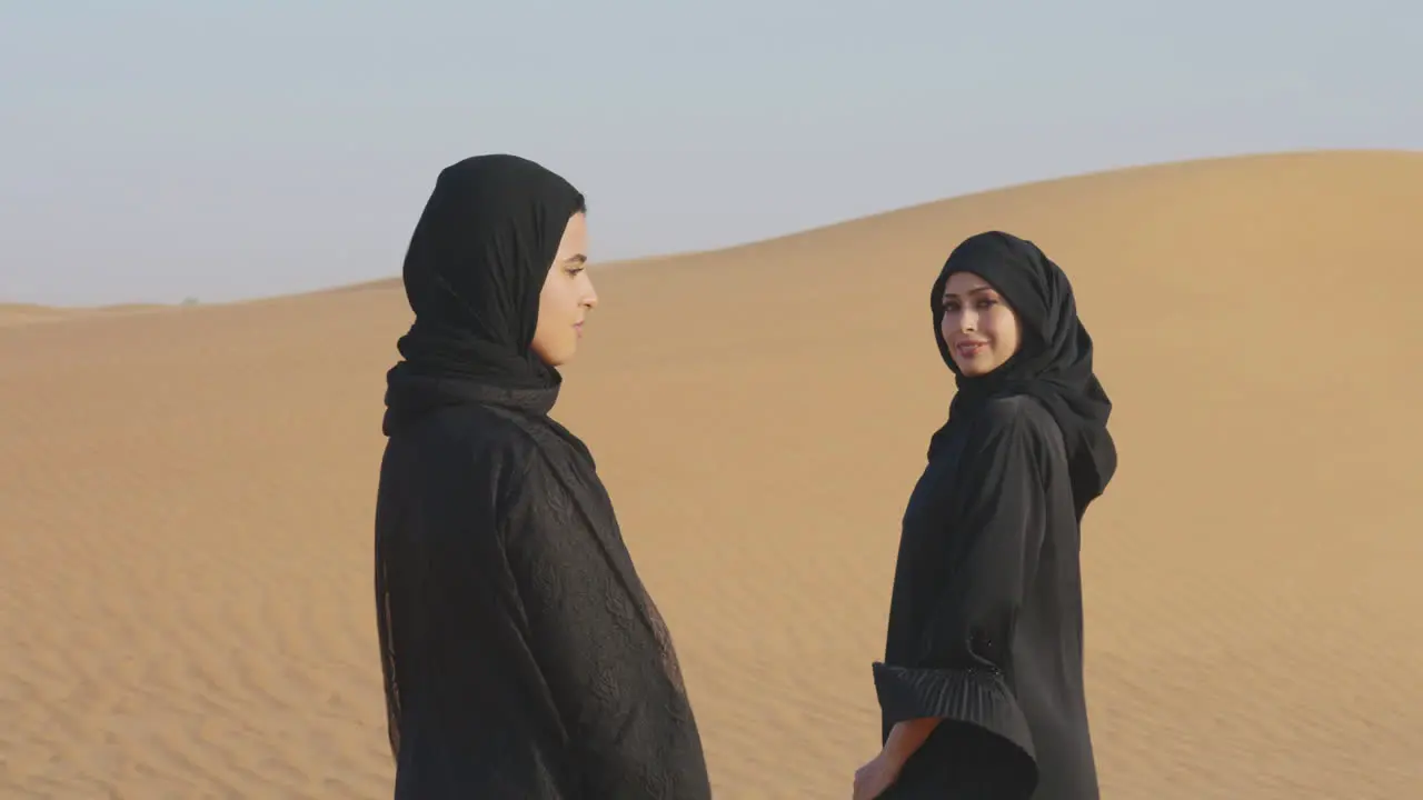 Dos Hermosas Mujeres Musulmanas En Hiyab De Pie En Un Desierto Ventoso Y Sonriendo A La Cámara