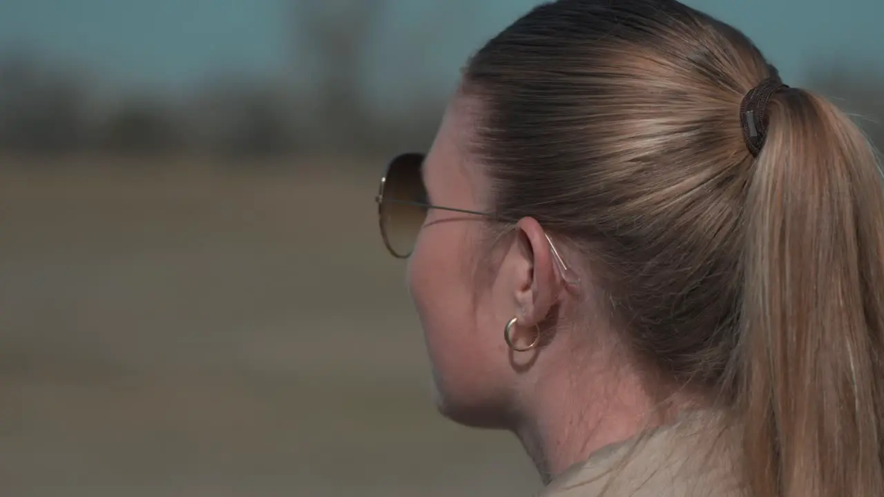 Woman with sunglasses is observing into distance during sunshine day blurred background video graded in pastel autumn colors people in nature concept