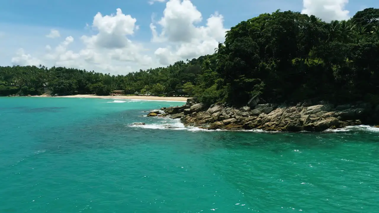 4K Cinematic nature aerial footage of a drone flying over the beautiful beach of Surin in Phuket Thailand on a sunny day