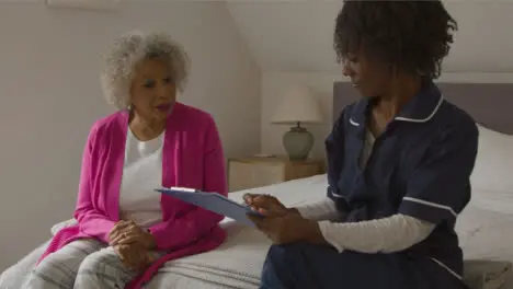 Middle Aged Nurse Conducts a Home Visit with Senior Woman