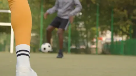 Close Up Of Young Couple Kicking And Passing Football On Artificial Soccer Pitch In Urban City Area 