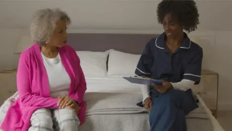 Middle Aged Nurse Conducting Home Visit with Elderly Woman