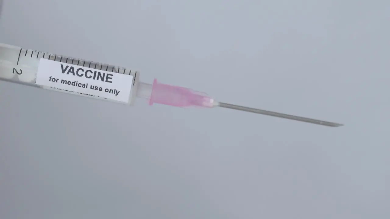 Syringe With Vaccine For Immunization Flip By A Finger With Glove Close Up