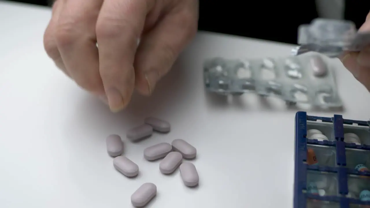 Man taking out medicine tablets from the blister pack unto a table Close up