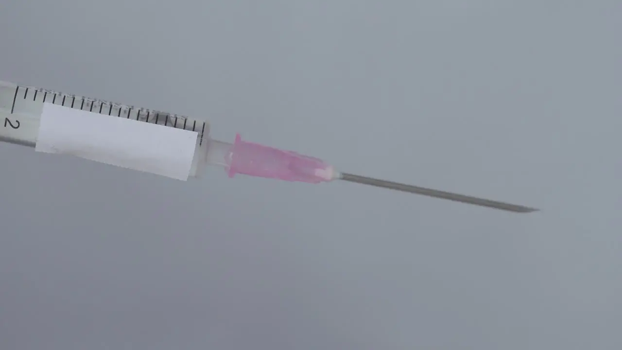 Syringe For Vaccination With Drops On Needle Being Flick By Finger Close Up