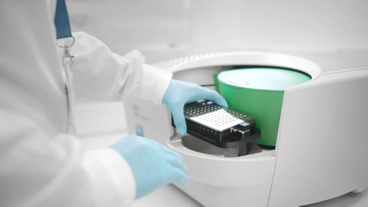 A lab assistant places samples under an innovative electron microscope for pharmaceutical bioscience research