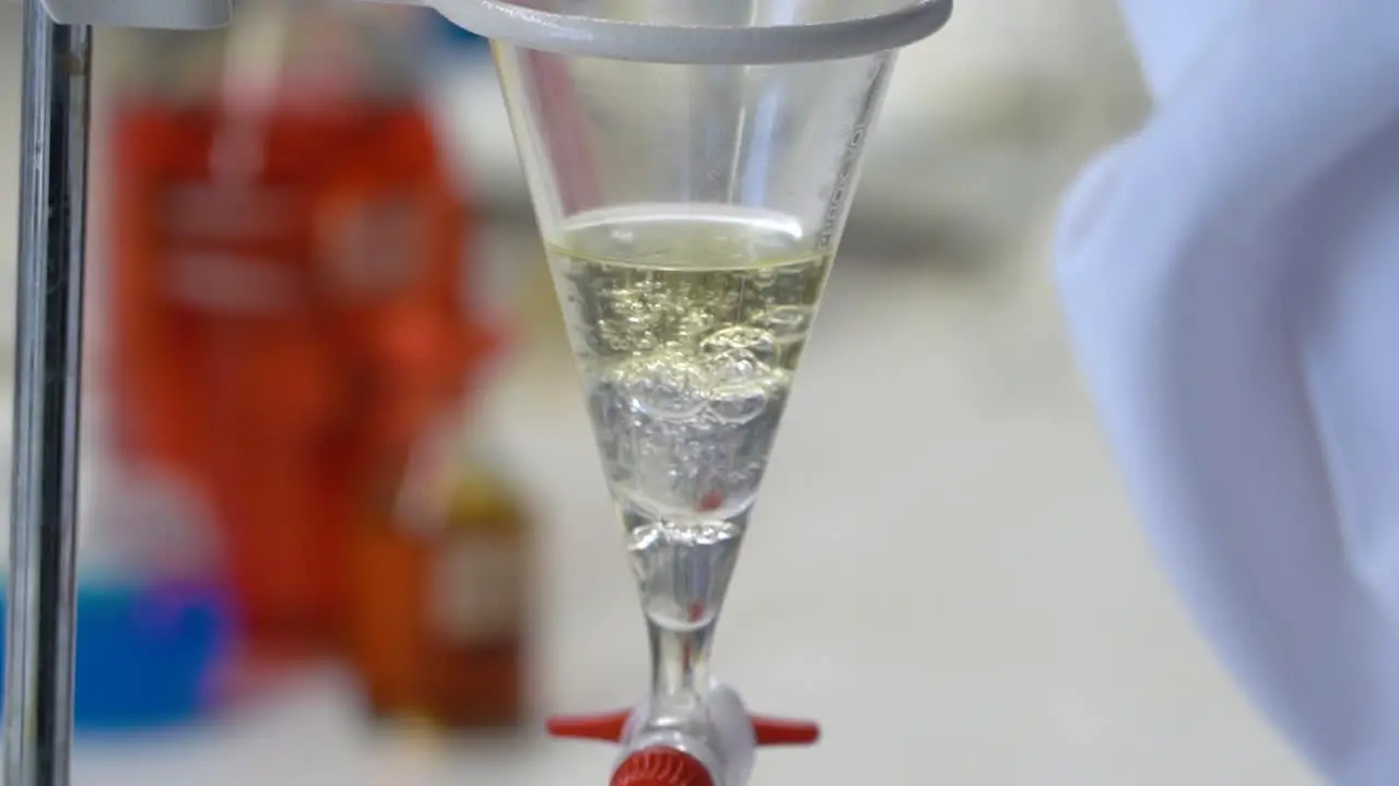 Science chemistry lab test close-up as a lab tech pours liquid into a funnel