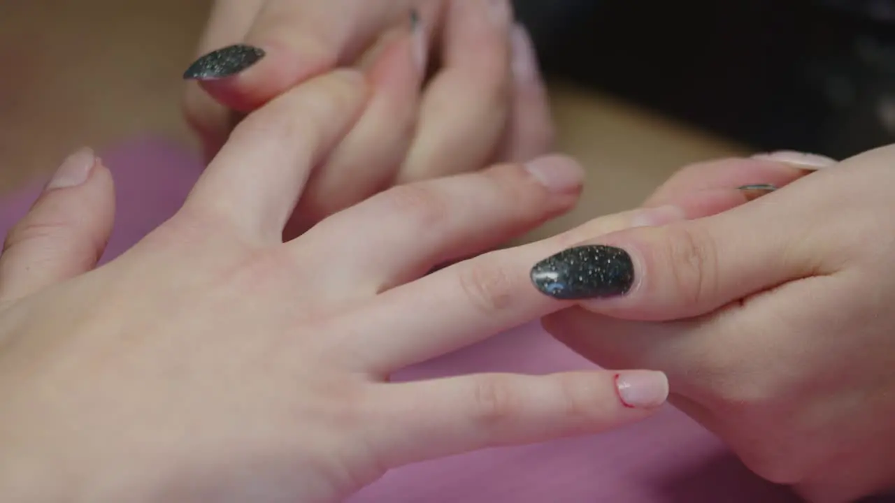 Manicurist Massaging Fingers Of Woman At Nail Salon