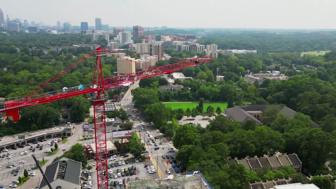 Aerial view of drone flying around red tall tower crane on construction site