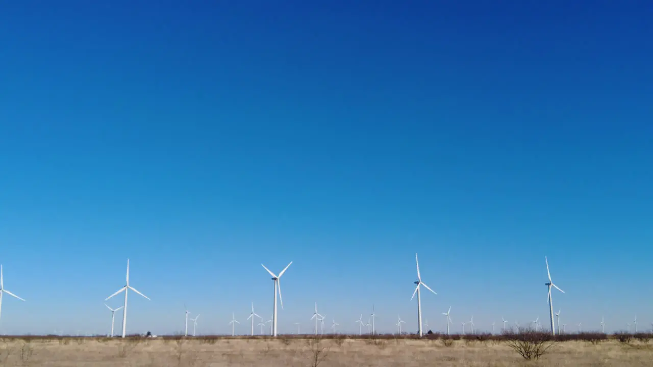 Slowly panning across a row of wind turbines in rural west Texas