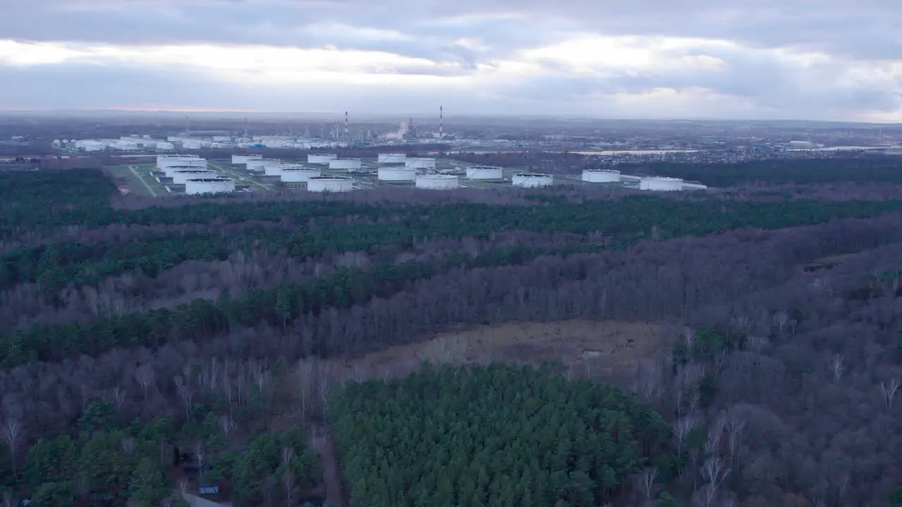 Aerial Flying Past Forest Landscape With Industrial Oil Storage Tanks In Background