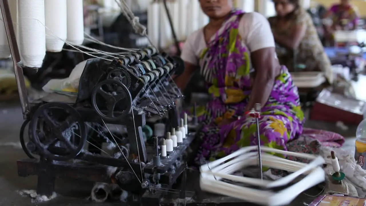 Rural poor Indian women spinning yarns at cottage industry to make cotton thread out of raw cotton women empowerment small scale industry slow tilt down shot