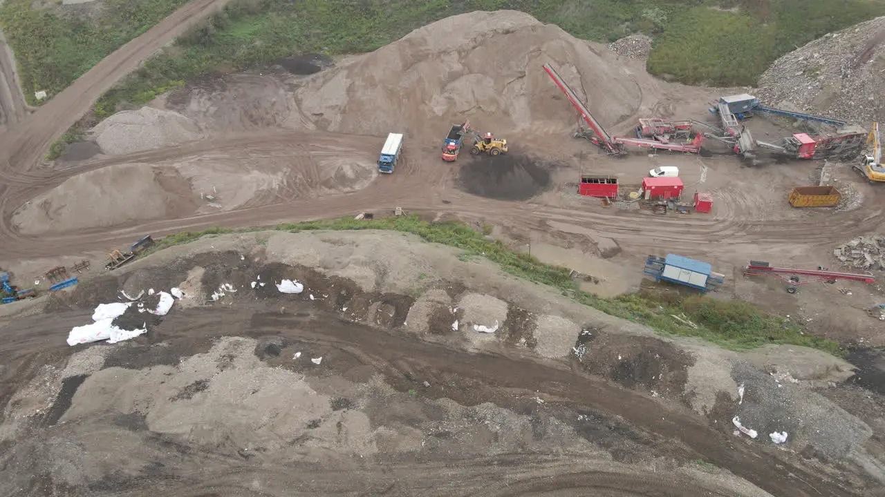 Aerial of excavator dumping sand in truck wide